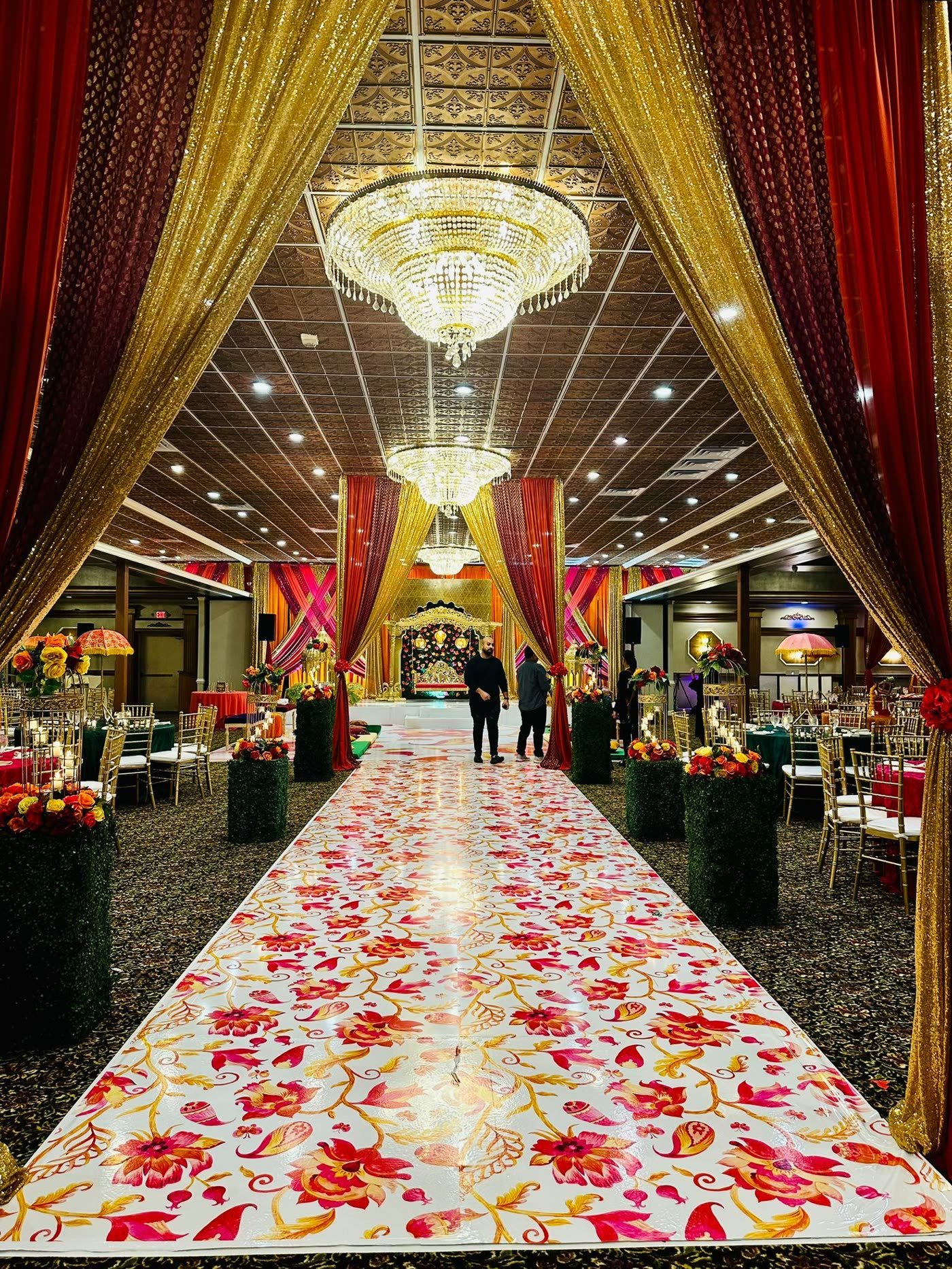 A petal-strewn aisle between red and gold drapery