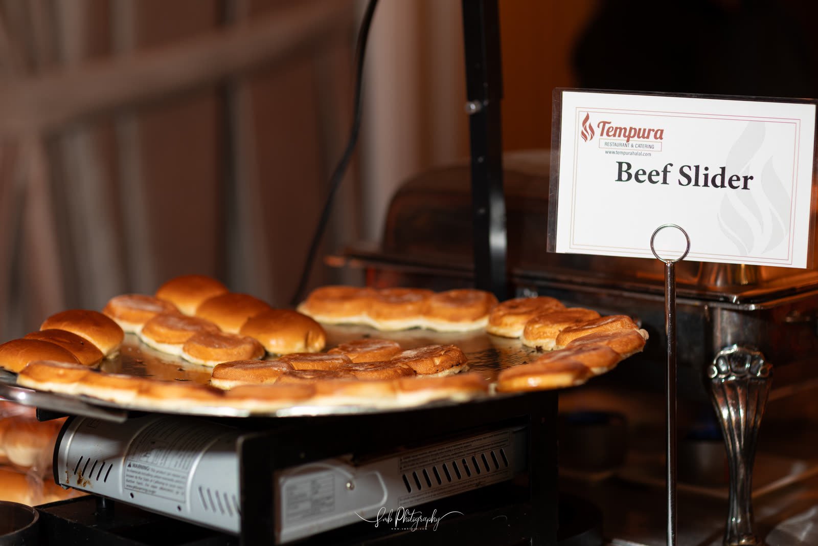 Beef sliders laid out under the sign