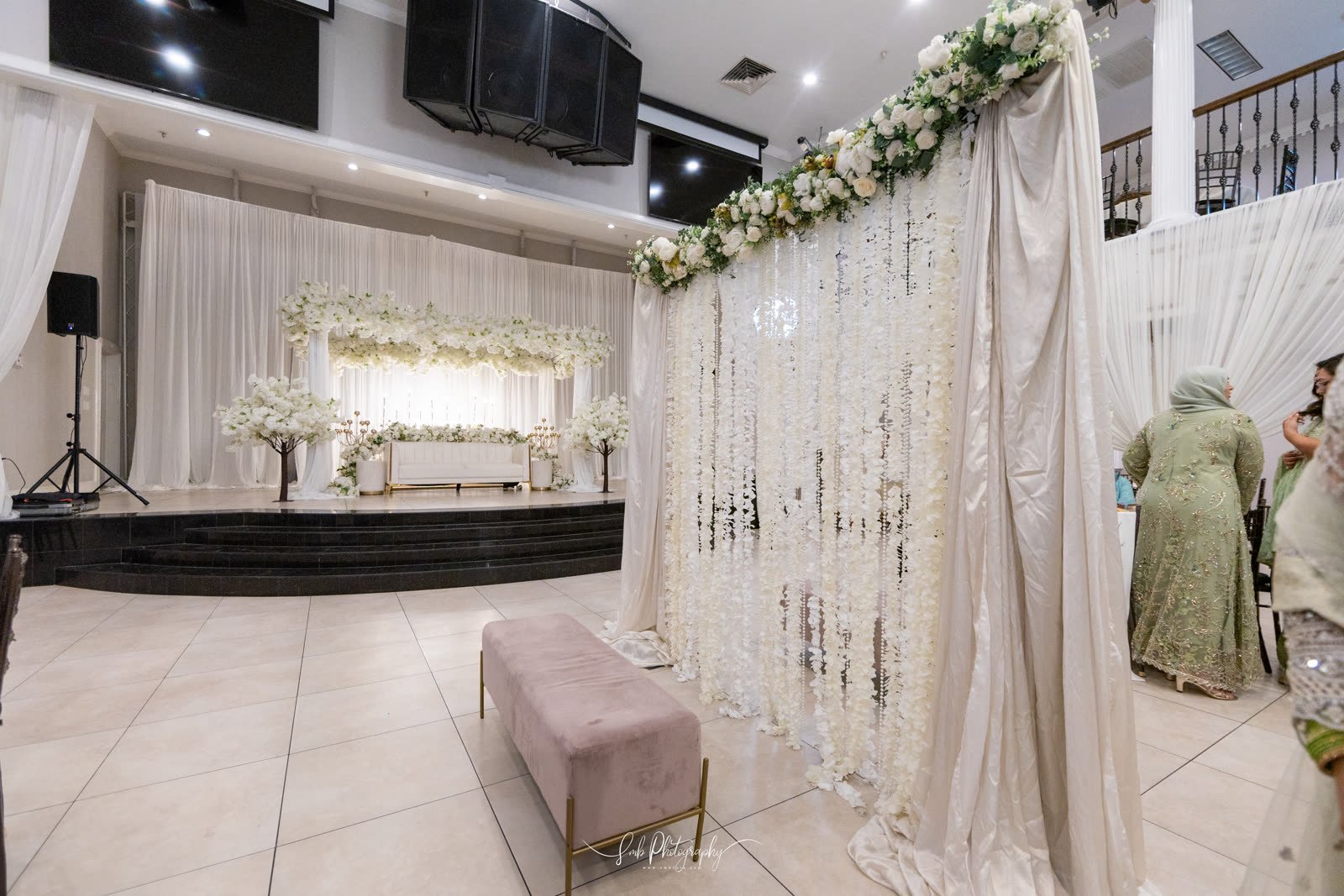 A white floral stage with hanging garlands