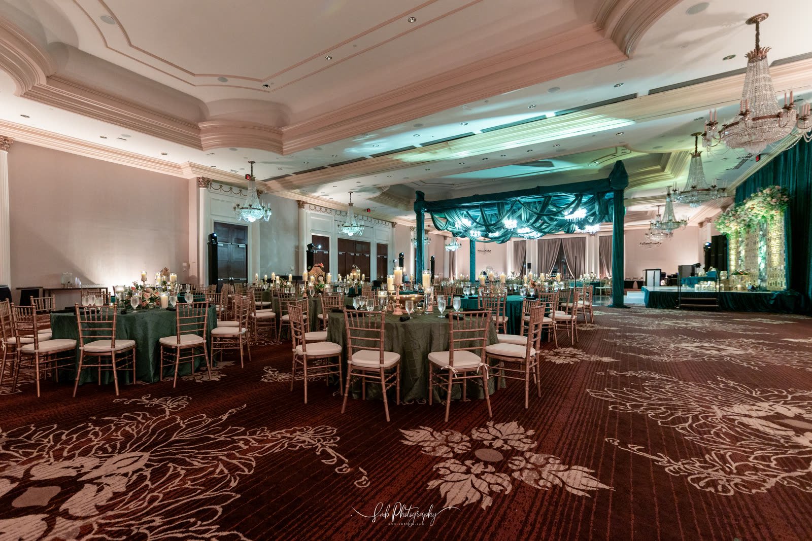 The main room laid out for a reception, teal drapes behind the head table