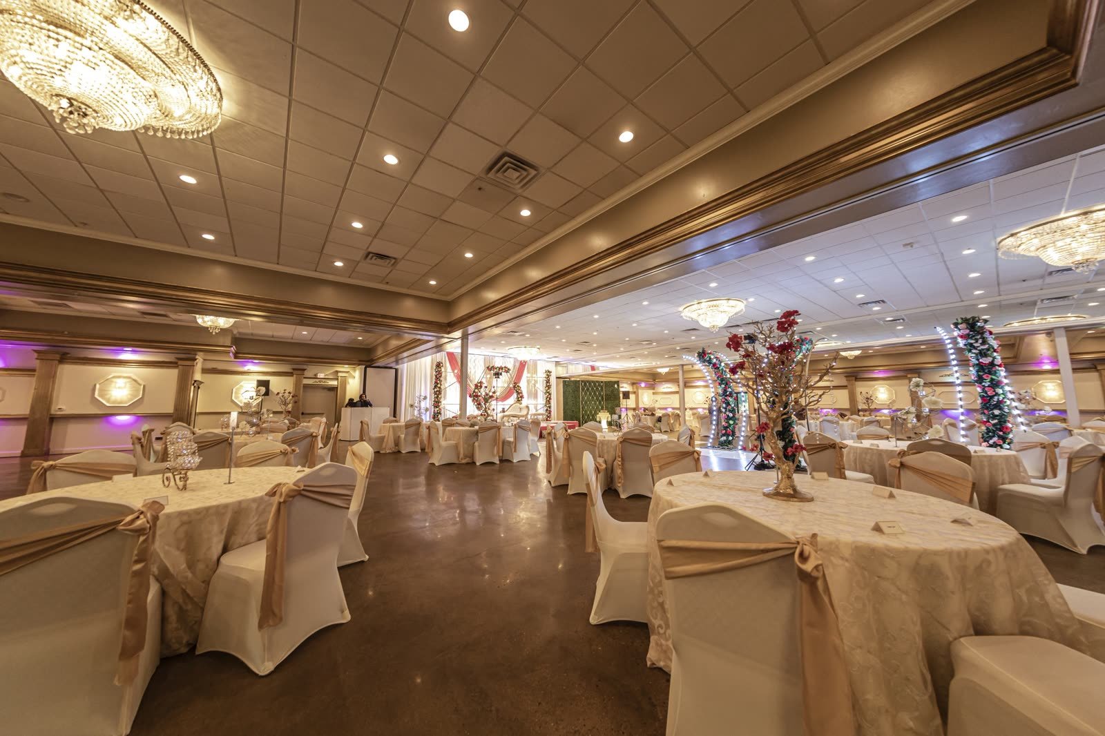 Gold linens and cream-draped chairs under the chandeliers